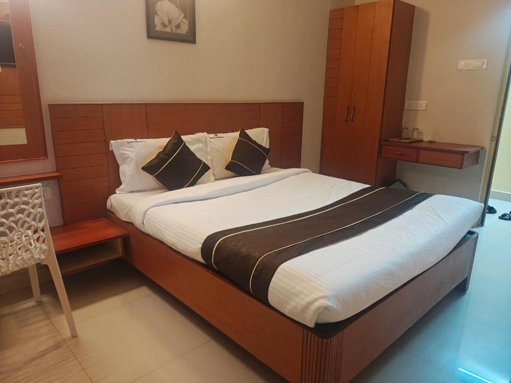 a bedroom with a large bed with a wooden headboard at skylink residency in Chennai
