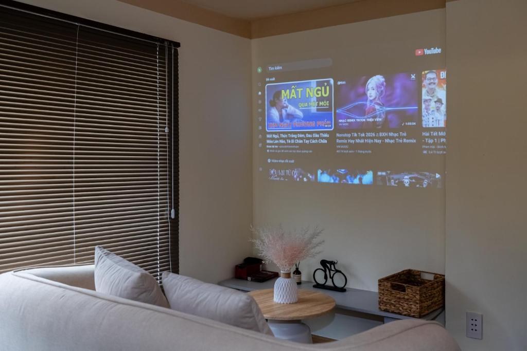a living room with a white couch and a large screen at Hội Home in Ho Chi Minh City