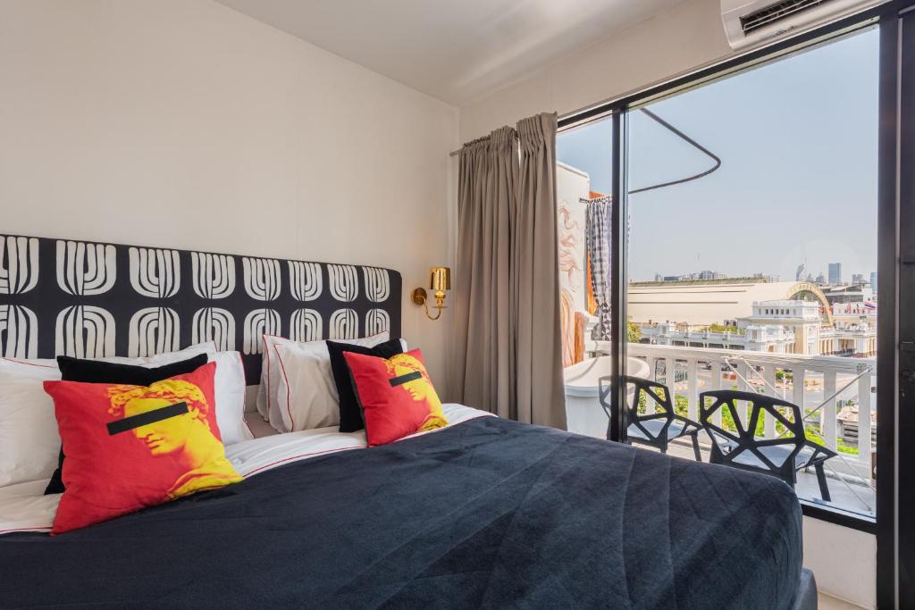a bedroom with a bed with colorful pillows and a balcony at Studio Kunst in Bangkok