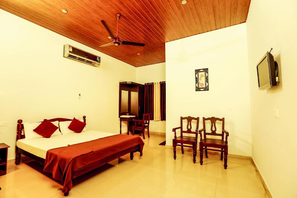 a bedroom with a bed and a table and chairs at Baywatch Beach Resort in Alleppey