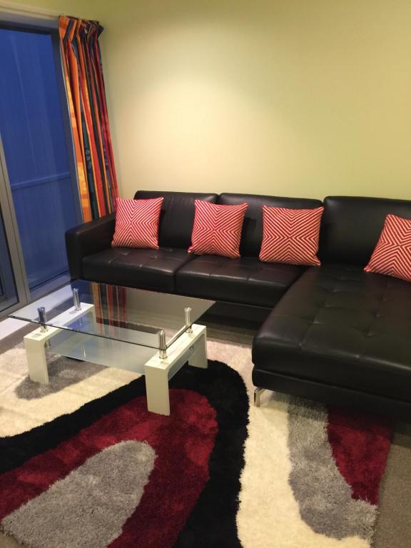 a living room with a black couch and a glass coffee table at DatePalm CBD & Central Akl in Auckland