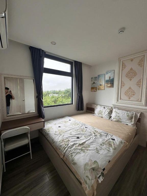 a bedroom with a large bed with a large window at Royal Apartment in Dien Ban