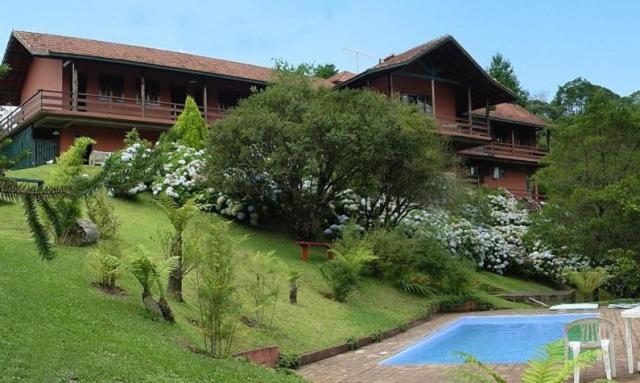 a large house with a swimming pool in front of it at Pousada da Trilha in Monte Verde