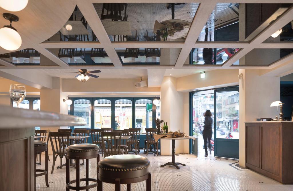 台北二十轮旅店大安馆的一间设有桌椅的餐厅,以及一位走进客房的人