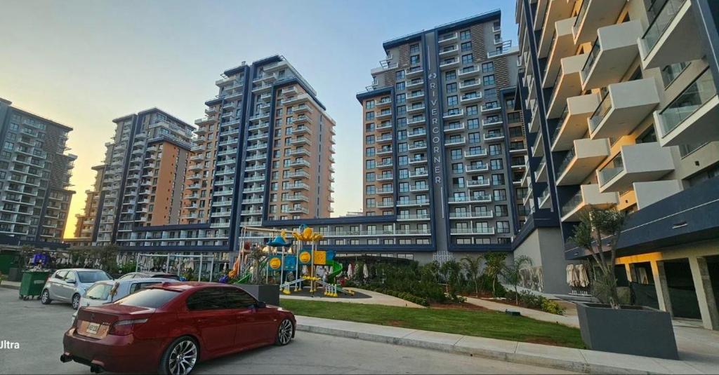 a red car parked in front of tall buildings at Riverside studio in Iskele in Dherinia