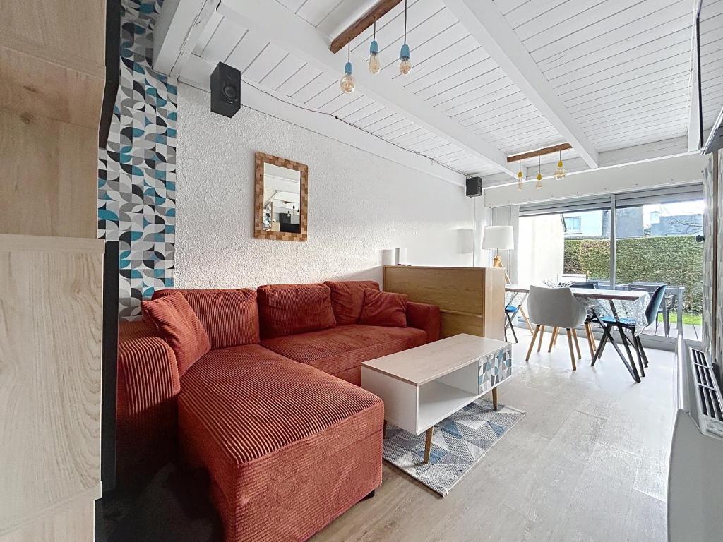 a living room with a red couch and a table at Escapade marine Carnac, Petite Maison toute équipée et confortable, au calme entre plage et ville avec jardinet au sud in Carnac