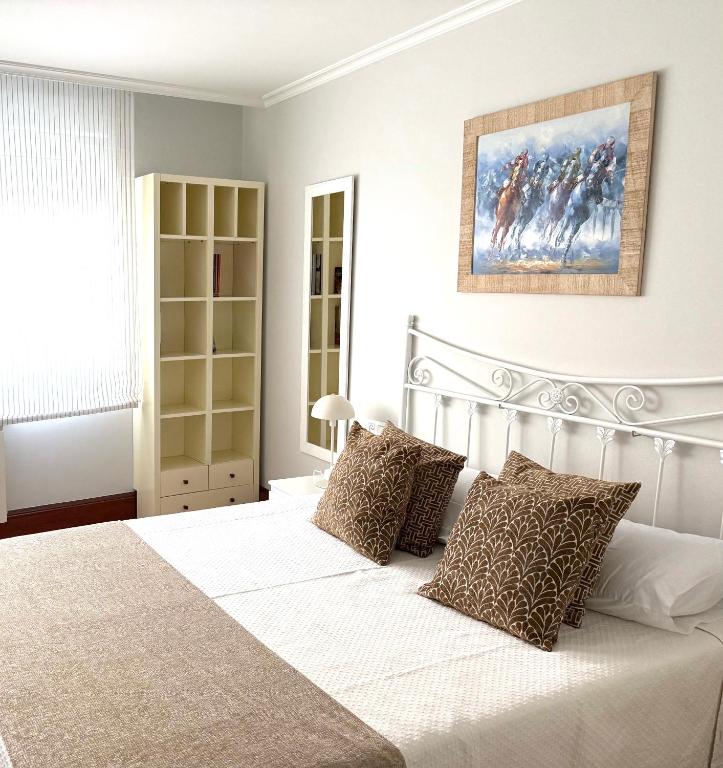 a bedroom with a white bed and a painting on the wall at A CALZADA in Cambados