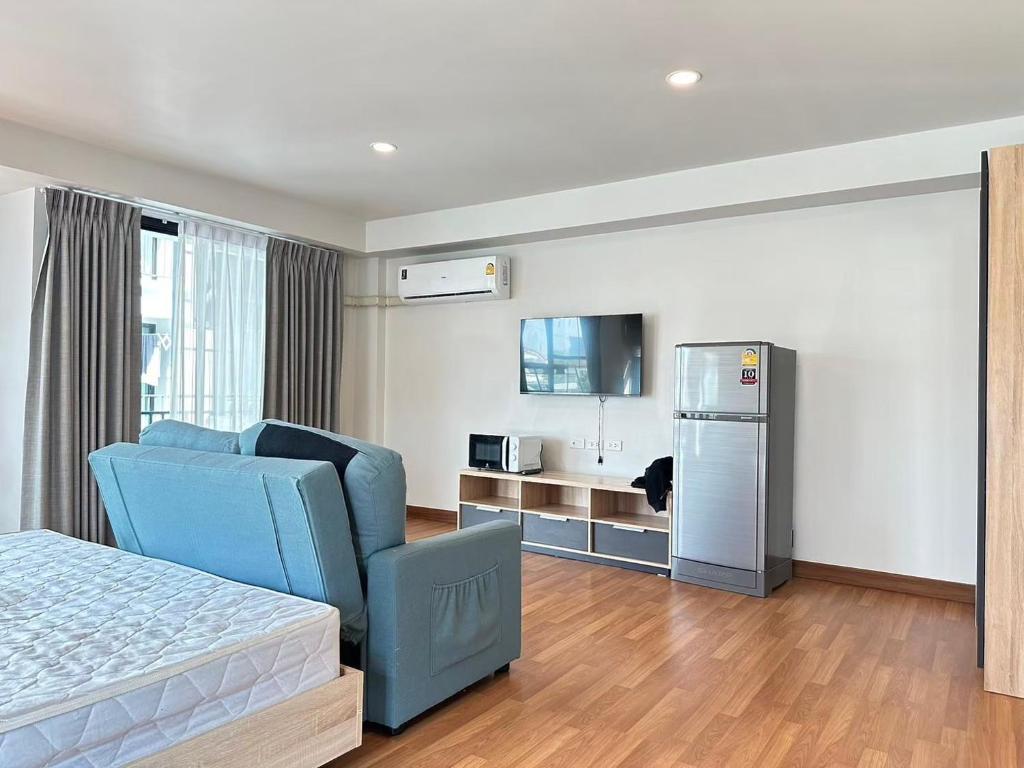 a bedroom with a blue chair and a refrigerator at Msthouse in Ban Bang Phun