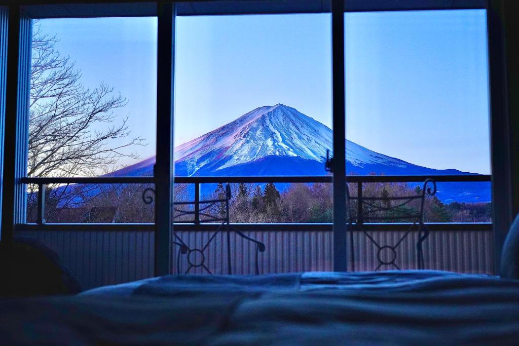 a view of a snow covered mountain from a bedroom window at Cocon富士 in Fujikawaguchiko