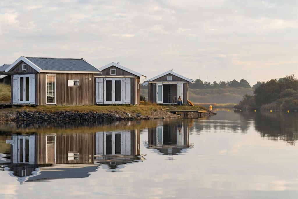 two houses on an island in a body of water at Brouwersdam Stay in Ouddorp