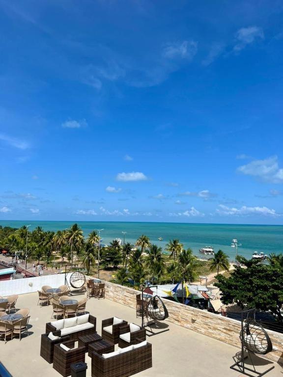 a patio with tables and chairs and the ocean at Nobile Imperial Flat in João Pessoa