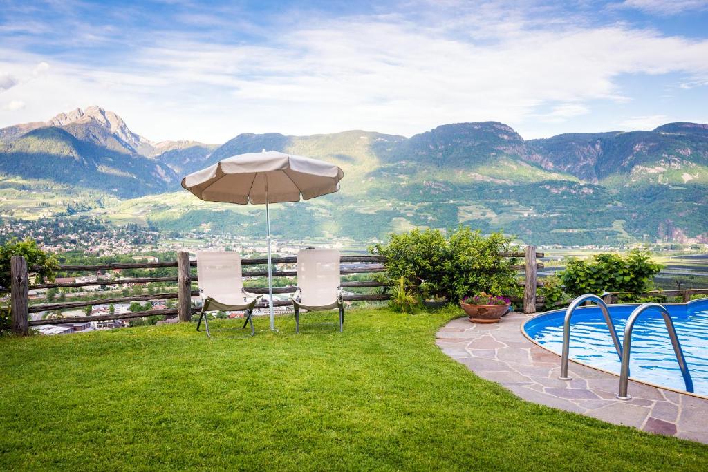 un patio con sombrilla, sillas y piscina en Weingut Pardellerhof, en Marlengo