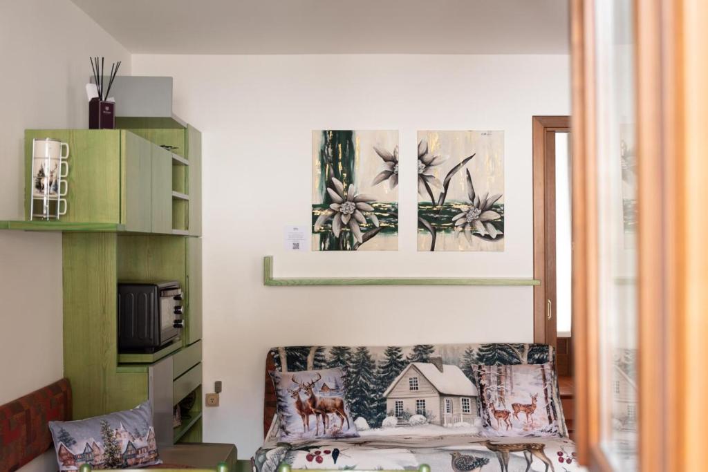 a living room with a couch and paintings on the wall at Villetta Eden Schilpario in Schilpario