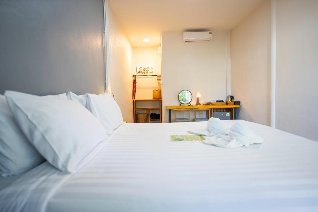 a white bed with white sheets and a clock on a table at Fix25House Koh Kood in Ban Khlong Mat