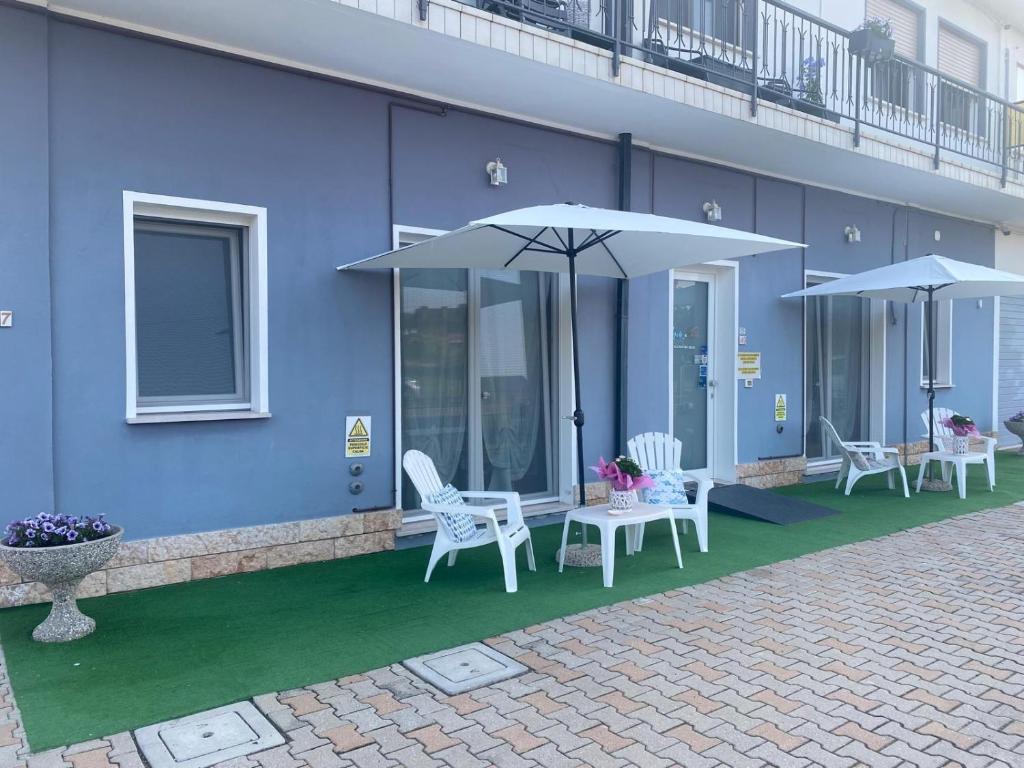 a blue building with white chairs and umbrellas at Mare&Terra... Alloggi nel Delta in Polesine Camerini