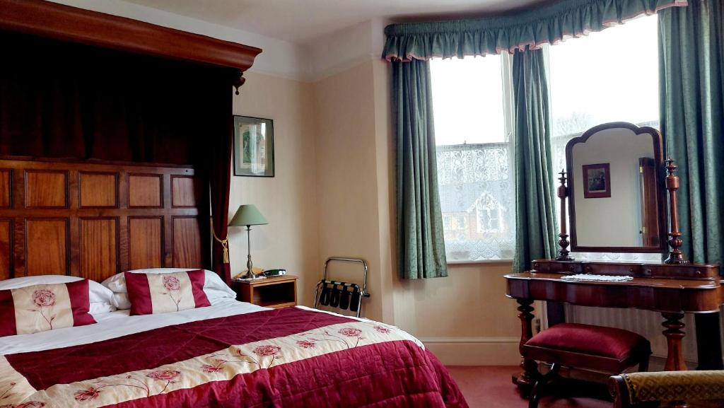 a bedroom with a large bed and a mirror at Banbury Cross B&B in Banbury