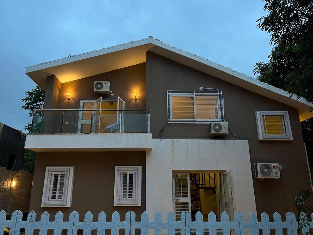 a house with a white fence in front of it at Nirvana Villa Karjat in Dhamni
