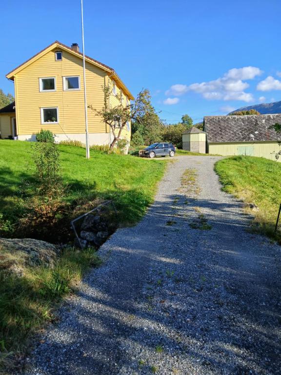 a gravel road in front of a yellow house at The house by the waterfall in Breim