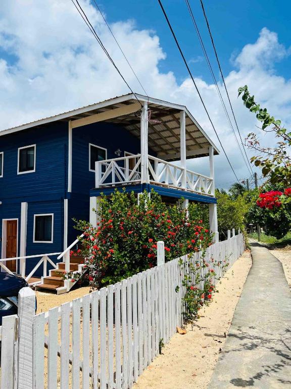 a blue house with a white fence and flowers at The Flying Toucan Beach Rentals in Placencia
