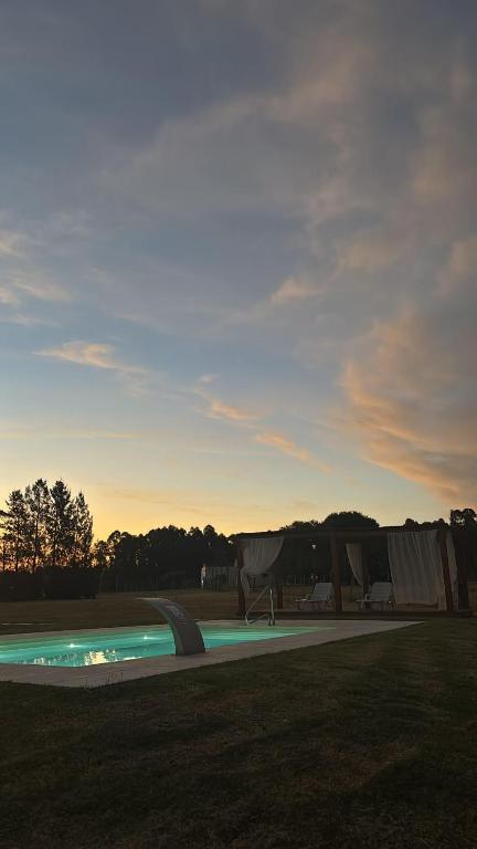 a swimming pool with a sunset in the background at Chacra Dosvistas in Maldonado