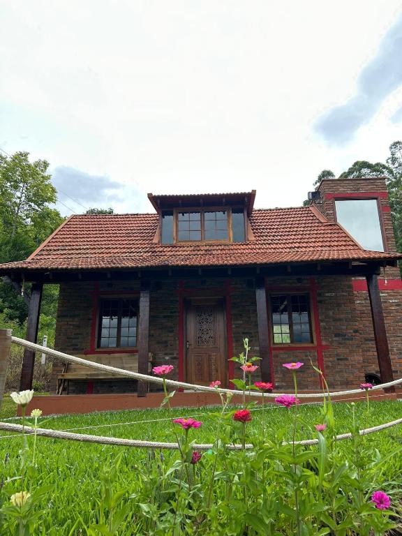 a brick house with a red roof and some flowers at Chale do Morro in Marques de Sousa