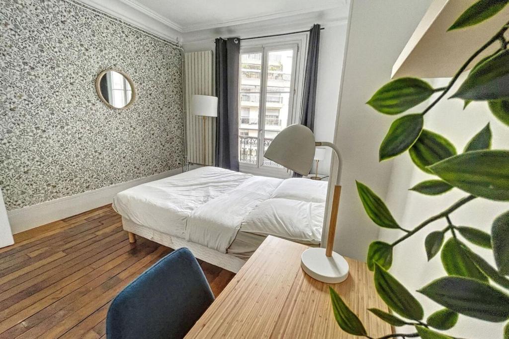 a bedroom with a bed and a table and a window at Room in elegant and charming 3-bedroom apartment near Bois de Vincennes in Paris