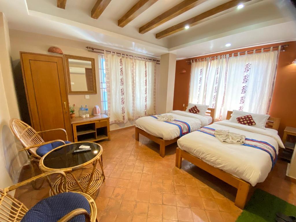a bedroom with two beds and a table and chairs at Kathmandu Metro Boutique Hotel in Kathmandu