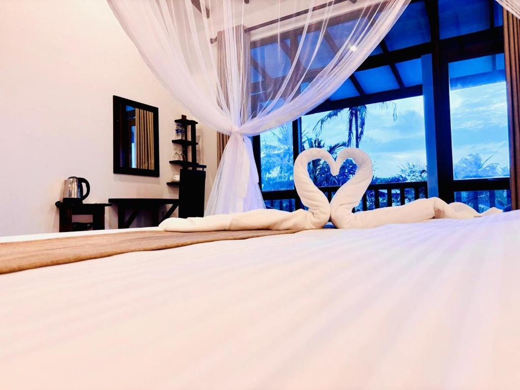 two hearts shaped towels on a bed in front of a window at Hotel Siyomin in Ahangama
