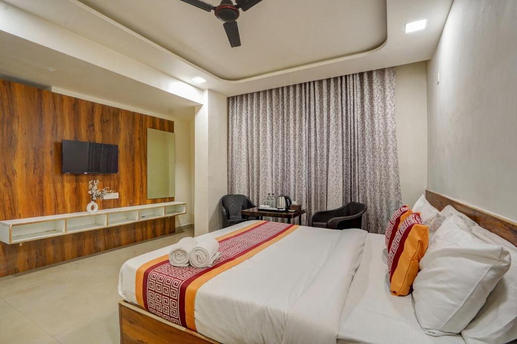 a hotel room with a bed and a tv at Hotel Sayba Inn - Budget Stay! in Pune