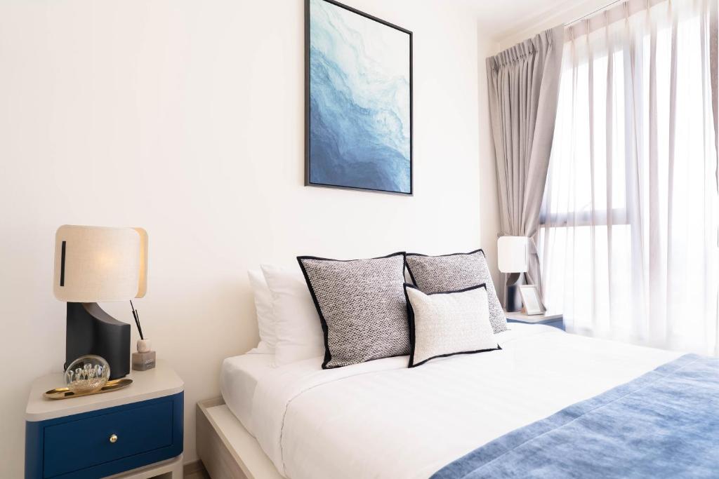 a white bedroom with a bed and a window at The Hampton Suites Bangna in Bangna