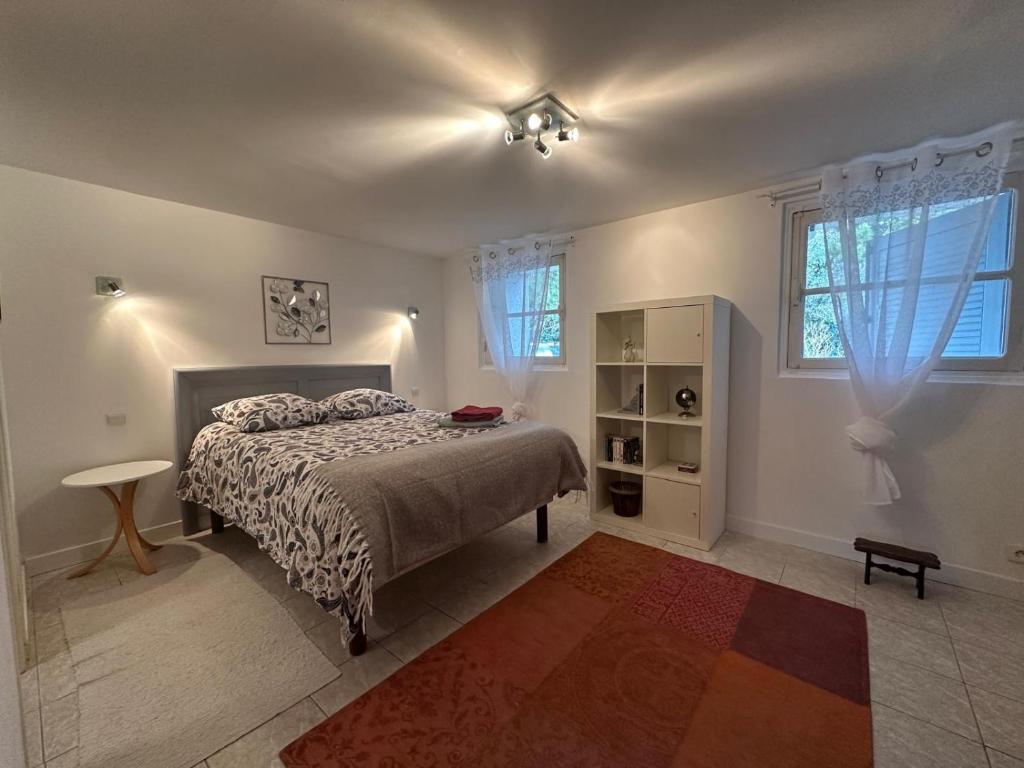 a bedroom with a bed and a table and windows at Beaurivage, studio privé dans maison d'hôte avec parc in Libourne