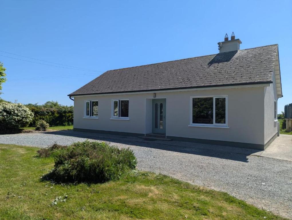 a small white house with a gravel driveway at Hook Lighthouse Cottage in Ramsgrange