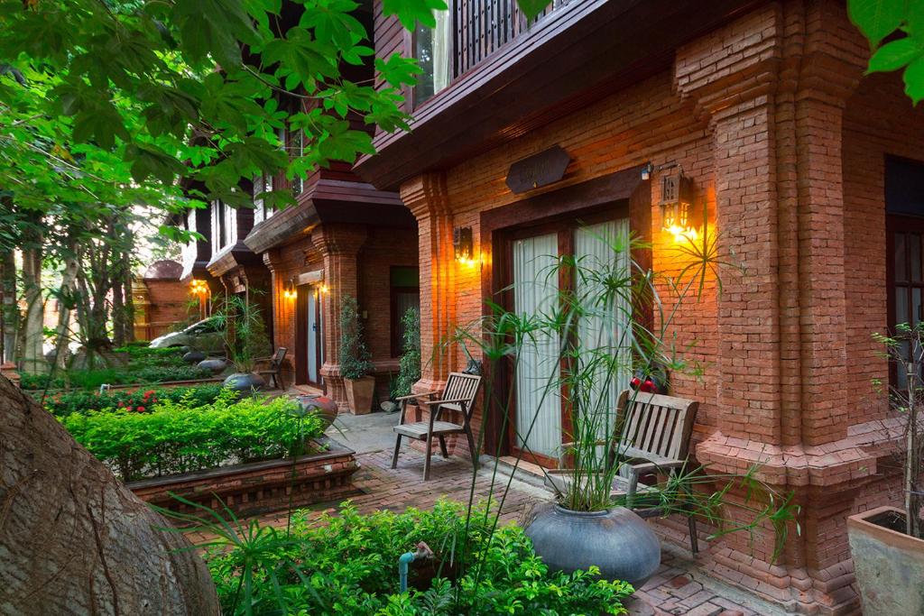 a brick house with a patio with chairs and plants at Baan Tawai Lanna Resort in Hang Dong