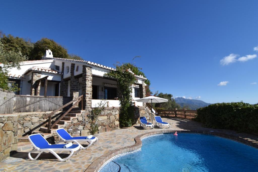 a villa with a swimming pool with chairs and a house at Finca Durillo with private Pool in Cómpeta