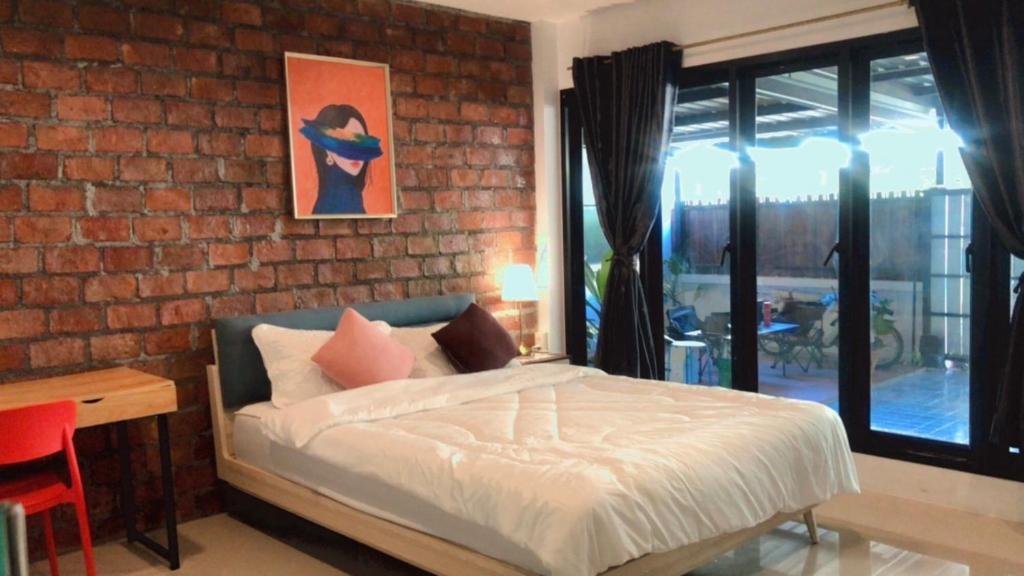a bedroom with a bed and a brick wall at SpamHouse Ranong in Ban Bang Rin (1)