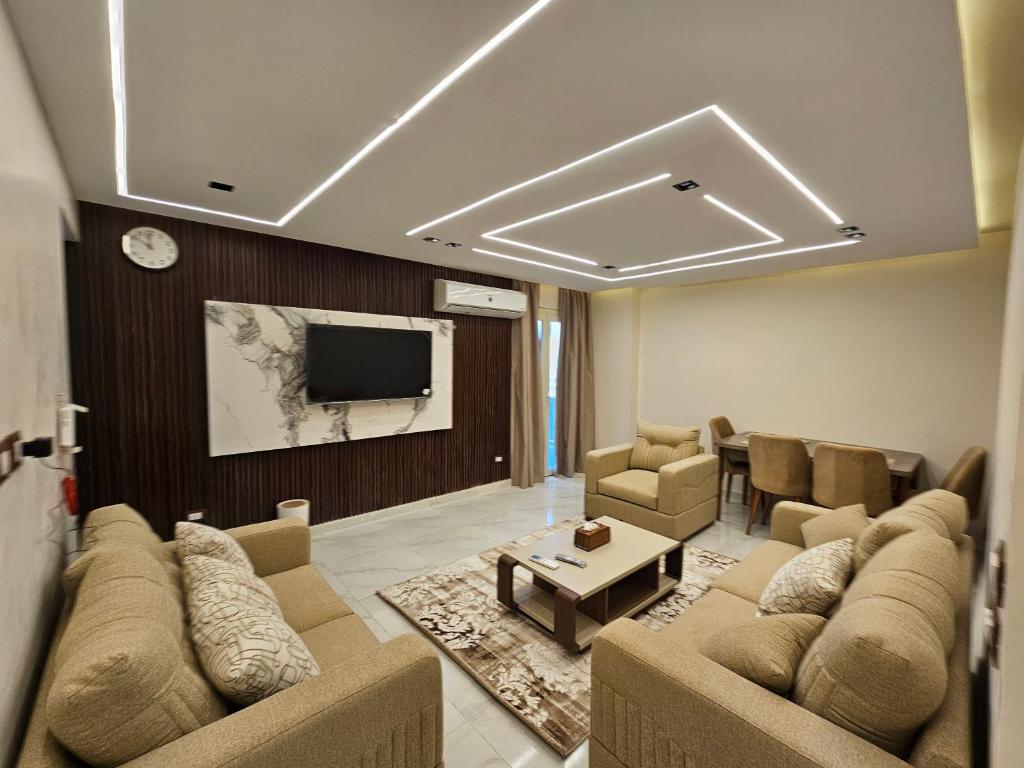 a living room with couches and a flat screen tv at Salalah Apartment in Cairo