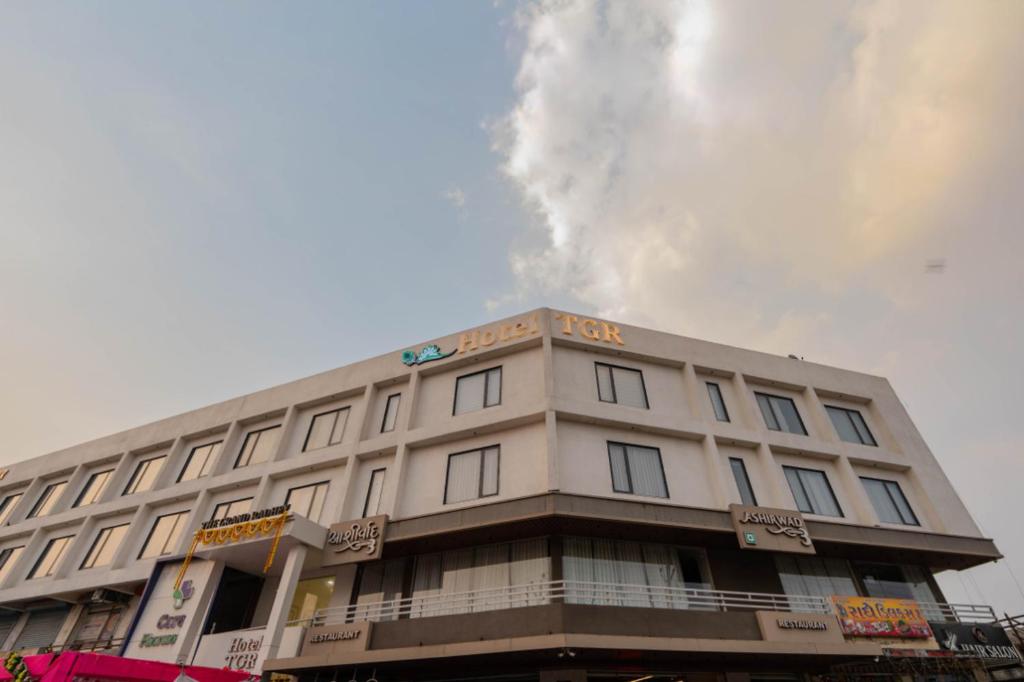 a white building with a sign on the top of it at Hotel TGR in Ankleshwar