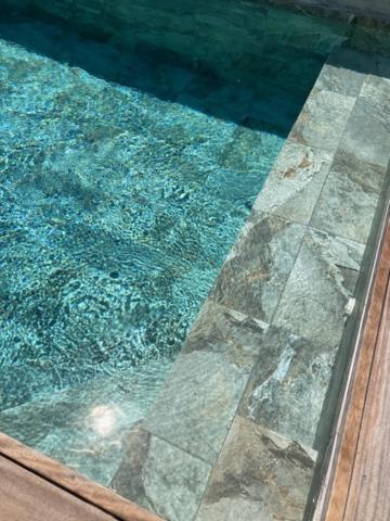 a swimming pool with blue water and a reflection in the glass at Dolce e Lumiu in Lumio