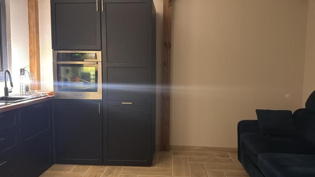 a kitchen with black cabinets and a microwave at Ranczo pod dębami in Wola Smolana