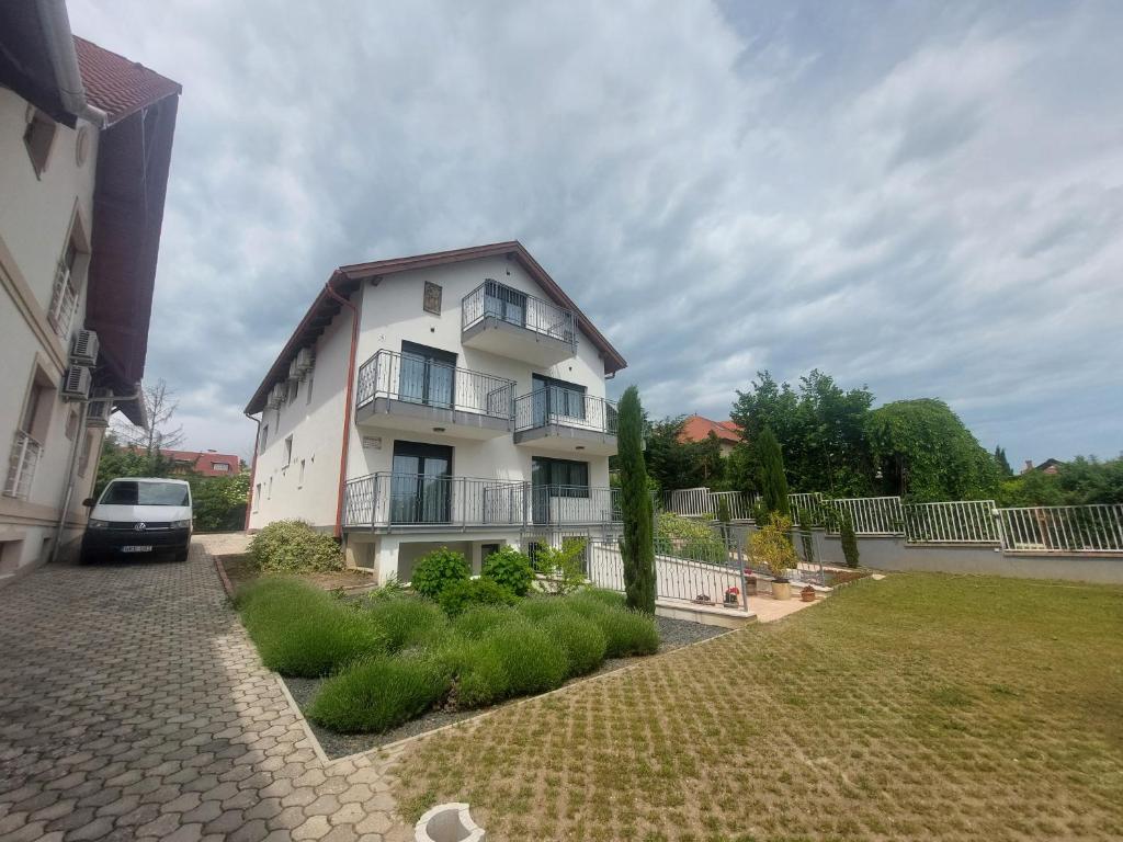 a white house with a car parked in front of it at Anton Apartmanház in Balatonfüred