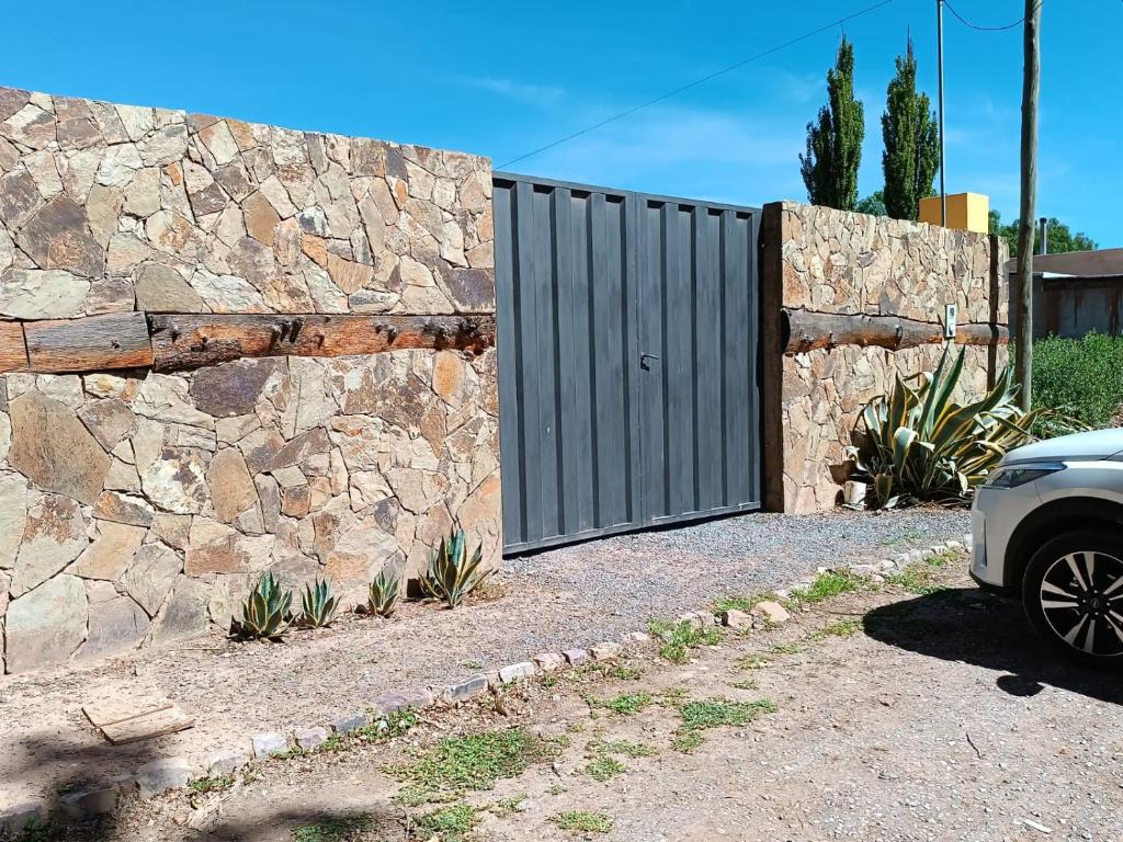 a stone fence with a gate in front of a car at Casa Verdes del Malka in Tilcara
