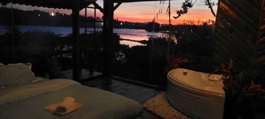 a bath tub and a bed in a room with a sunset at Nhà Bên Hồ in Bảo Lộc