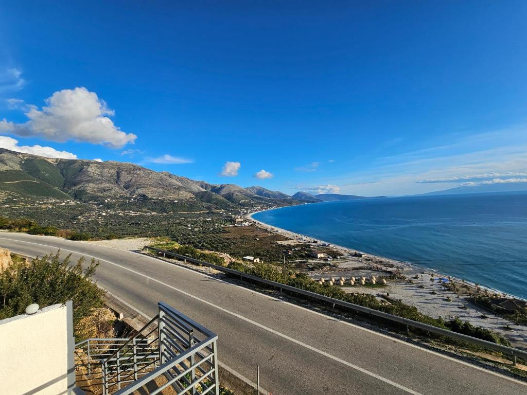 an empty road next to the ocean on a hill at Rafa's Apartament in Himare