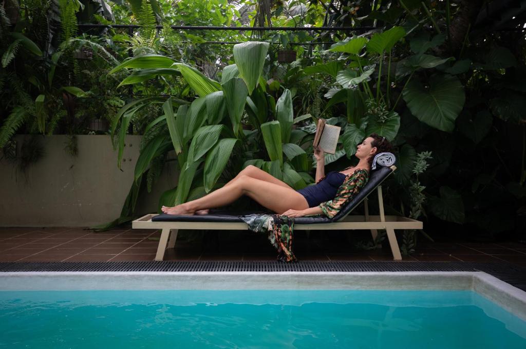 a woman sitting in a chair reading a book next to a pool at Sea Cloud Dalawalle in Unawatuna