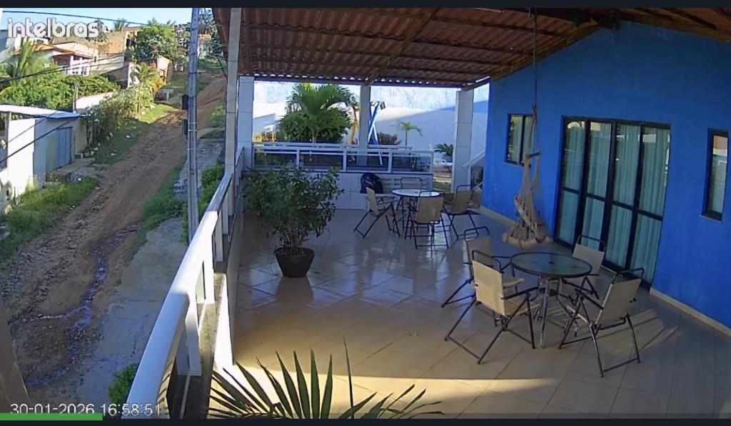 a patio with tables and chairs on a blue house at Temporada Monte gordo in Camacari