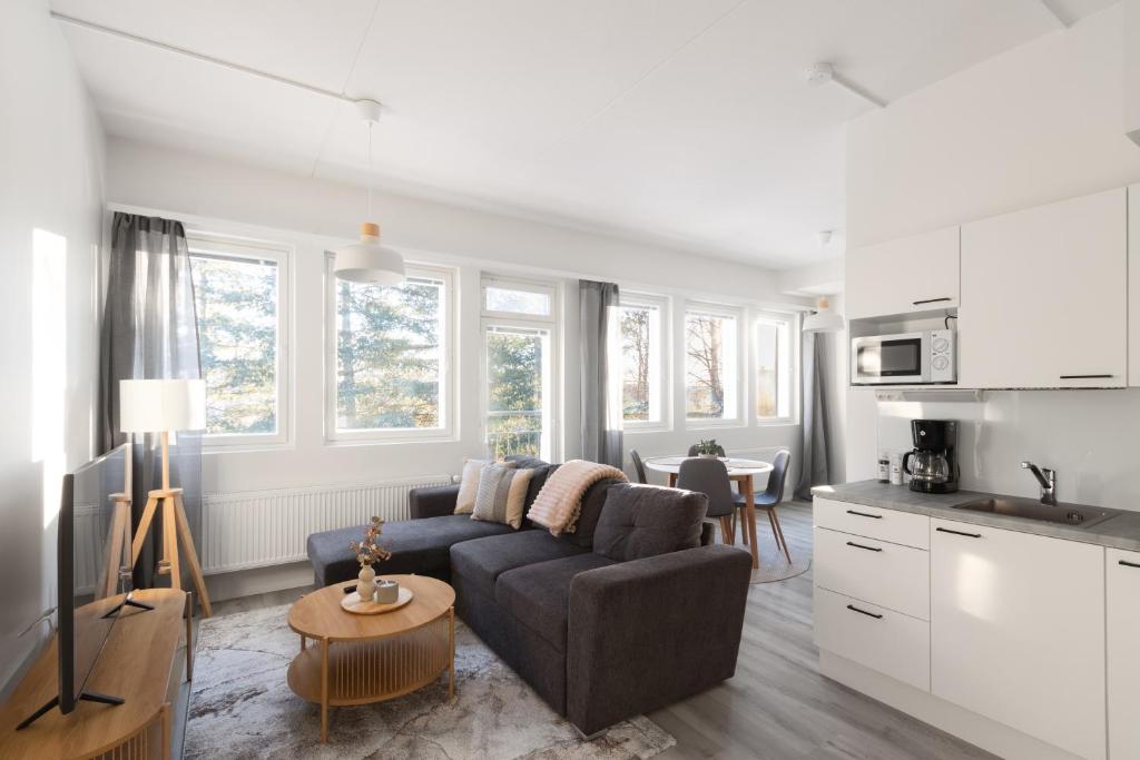 a living room with a couch and a kitchen at Pramea Apartments Tourula in Jyväskylä