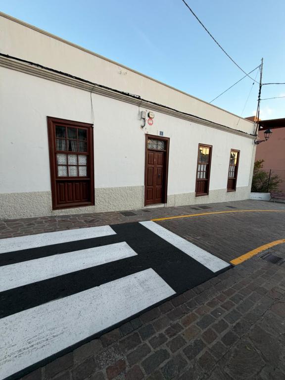 a white building with brown doors on a street at Casa Antigua Arona in Arona