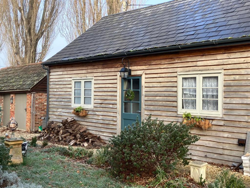 a small house with a blue door and windows at Deco Artist Cottage in Tytherton Lucas