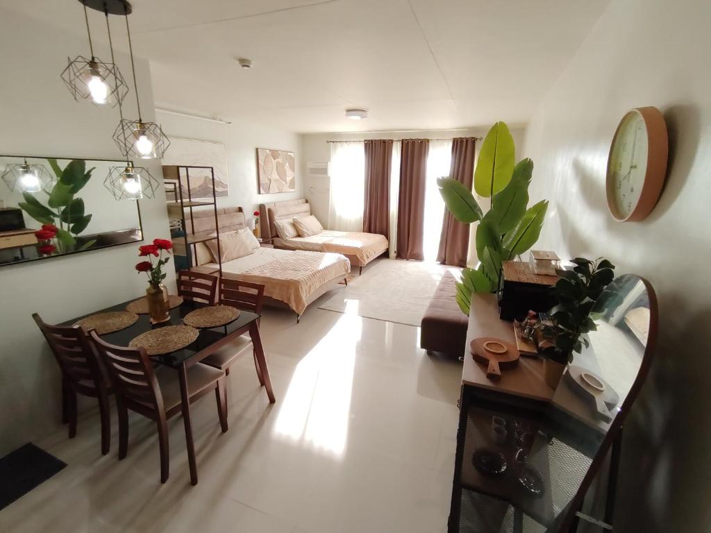 a living room with a table and a couch at Puerto Princesa Studio Condo with 2 Large Beds, Balcony, Pool & Gym in Puerto Princesa City