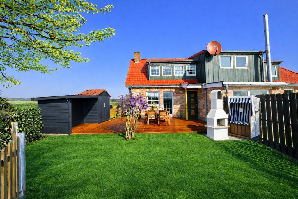 a house with a fence and a yard at "Huus ant Diek", Ferienhaus mit Maisonette Wohnung in Deichnähe, Nähe Norddeich in Norden